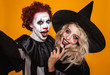 Photo of wizard woman and joker man wearing black costume and halloween makeup taking selfie, isolated over yellow background