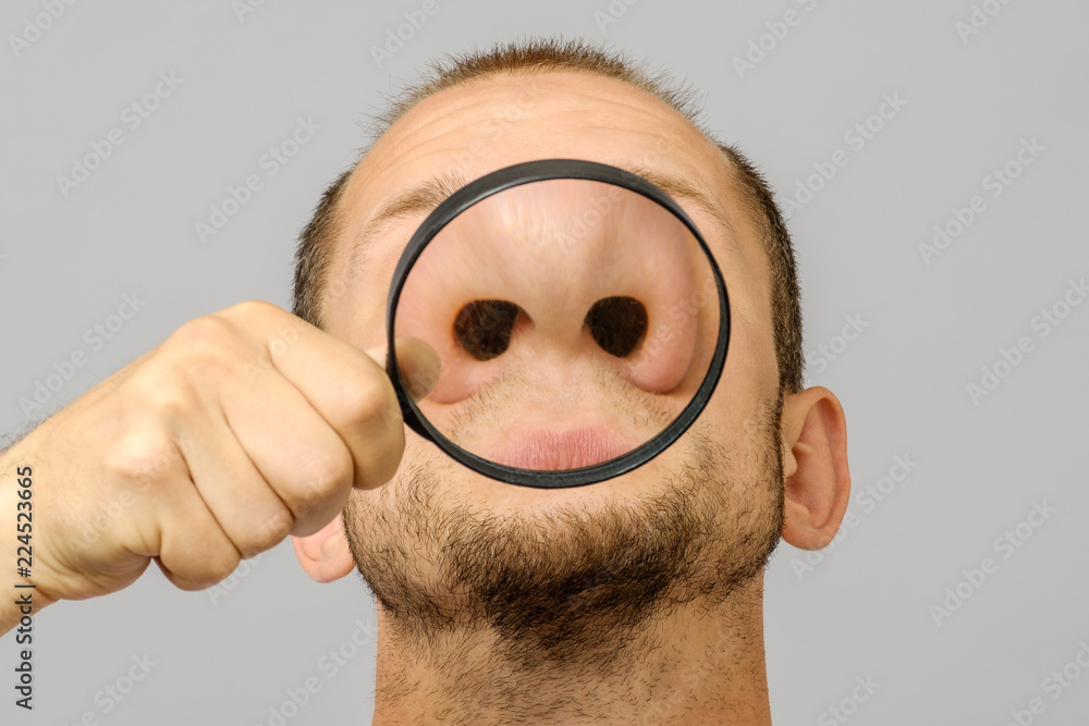 Portrait of caucasian man with magnifier makes fun face - obrazy, fototapety, plakaty 