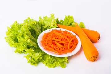 two carrots, sliced carrots on a white plate and lettuce leaves 