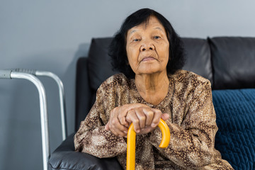 Wall Mural - Senior woman with cane resting and sitting on couch