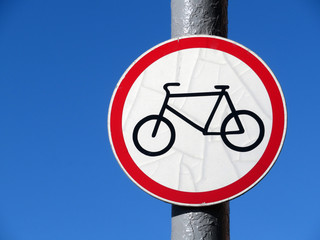 Bicycle road sign isolated on blue sky. Black bicycle symbol on the white circle