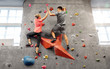 © Syda Productions - fitness, extreme sport and healthy lifestyle concept - young man and woman bouldering on a rock climbing wall at indoor gym and making high five gesture