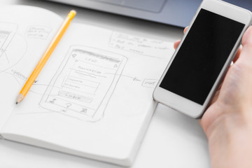 Wall Mural - app design, technology and business concept - hand of web designer or developer with smartphone and 
