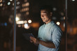 © mavoimages - Smiling Asian businessman using a tablet late at night