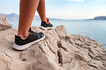 Wall Mural - close up legs of hiker young woman on trekking trail along sea bay