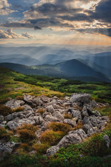 Wall Mural - Mountain hill with stormy sky and sunbeam at sunset