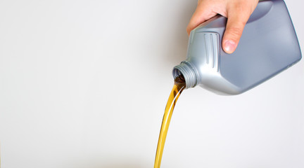 automotive oil in a hand a gray bottle on a light background