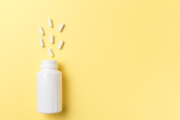 Assorted pharmaceutical medicine pills, tablets and capsules and bottle on yellow background. Top view. Flat lay. Copy space. Medicine concept. Heap of pills on yellow background