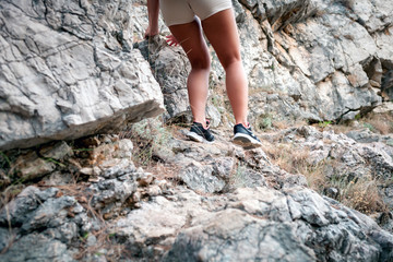 Wall Mural - legs of hiker girl hiking on trail near rocks