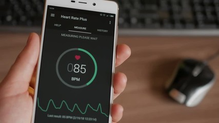 Man Looking At Health Monitoring App On Smartphone. Monitoring the heart pulse with a health application on smartphone.