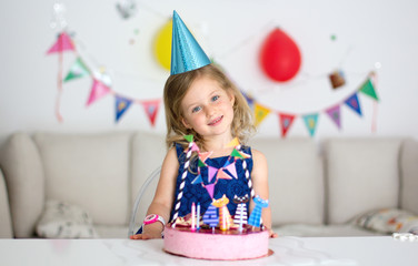 Happy little girl with birthday cake. Celebrate Happy Birthday Party with colorful decor.