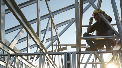 Sticker - Contractor Worker with Walkie Talkie in Hand on the Steel Frame of the House