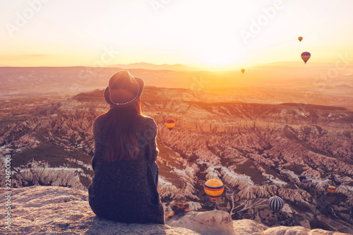 Fotografía A girl in a hat on top of a hill in silence and loneliness admires the calm natural landscape and balloons