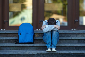 Schoolboy crying in the yard of the school