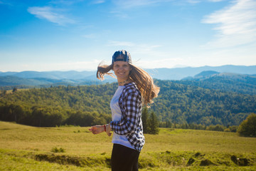 Young happy woman on top of hill enjoy beautiful view of sky and mountains, freedom and harmony concept