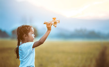 Cute Asian Child Girl Playing With Toy Wooden Airplane In The Field At Sunset Time In Vintage Color Tone