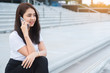 Young asian business woman in casual calling someone on phone and looking away.