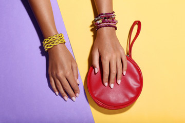 Canvas Print - Female hands with bracelets and red handbag on colorful background