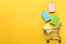 Small Paper Shopping Bags With Shopping Cart On Yellow Background