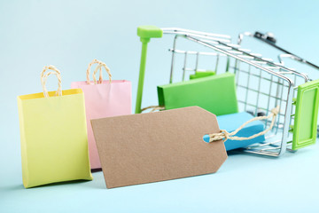 Wall Mural - Small paper shopping bags with shopping cart on blue background