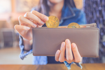 Woman hand is pulling a bitcoin out of a wallet.