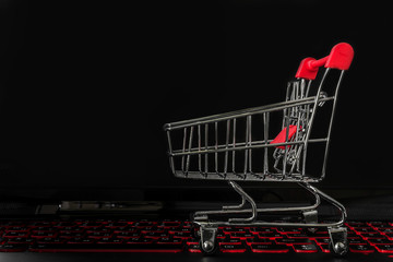 Online shopping / ecommerce and delivery service concept : Paper cartons with a shopping cart or trolley logo on a laptop keyboard, depicts customers order things from retailer sites via the internet.