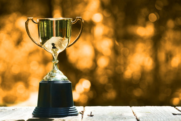 Wall Mural - trophy on wood table with yellow bokeh background , win concept