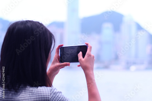 Photo Woman is taking photo with smart phone of city view in Hong Kong.