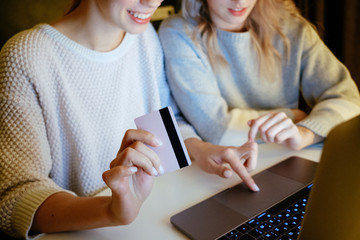 Girls make purchases on the Internet at home on a computer with a card