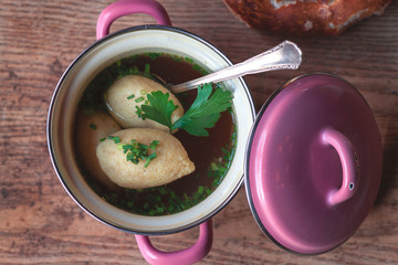 Wall Mural - heiße bayerische Grießnockerlsuppe Brühe für den Winter in einem kleinen Top mit Breze auf einer Berghütte Wirtshaus gegen Erkältung