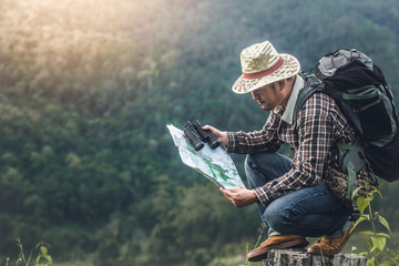 hiker with backpack sitting and look at map and checking on wood