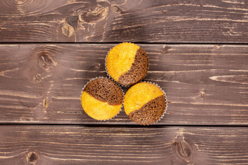 Group of three whole fresh baked marble muffin flatlay on brown wood