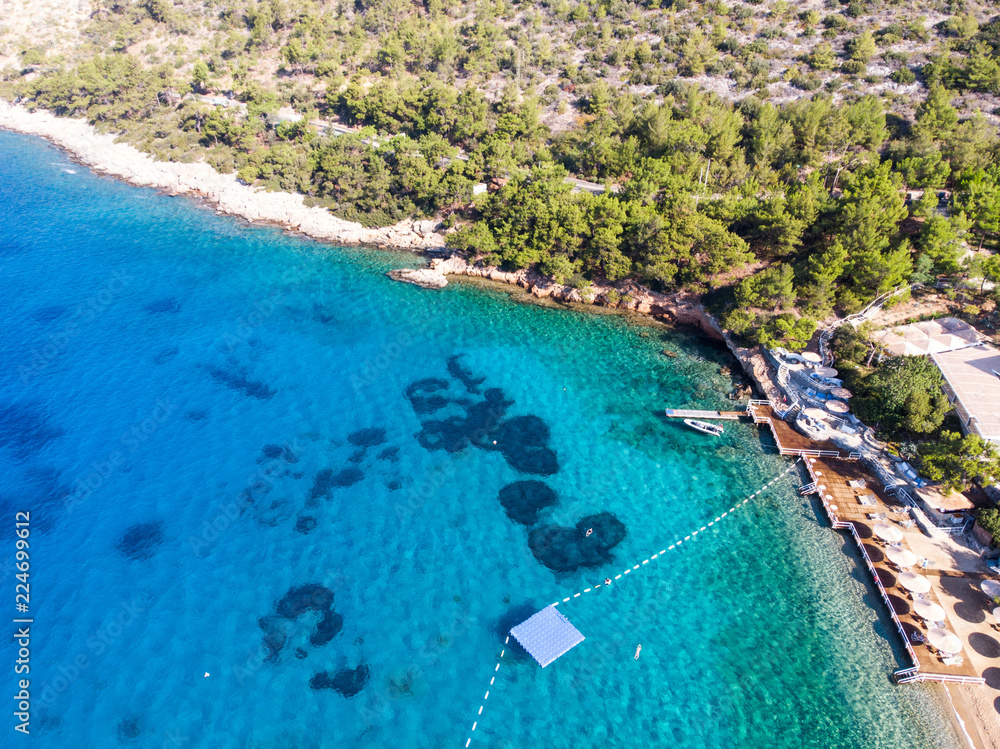 Aerial View of Beach Cove with Sunbeds, Blue Turquoise Sea and Trees - obrazy, fototapety, plakaty 
