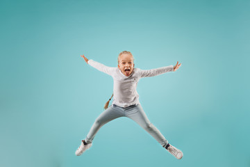 Wall Mural - Adorable small child at blue studio. The girl is jumping and smiling. Young emotional surprised teen girl. Human emotions, facial expression concept.