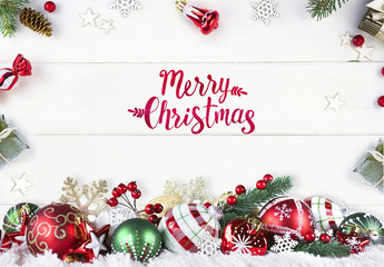 Greeting Festive Christmas composition of green and red balls on white wooden boards in frame fir branches, gifts with with an inscription Merry Christmas!