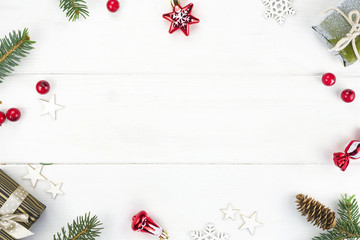 Wall Mural - Christmas composition, frame. Christmas gift, fir branches and cones, red berries,  snowflakes, Christmas tree toys on wooden white background, top view. Flat lay, copy space.