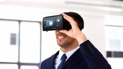 Wall Mural - business, technology and augmented reality concept - businessman with vr glasses or headset and cube 3d rendering on screen at office