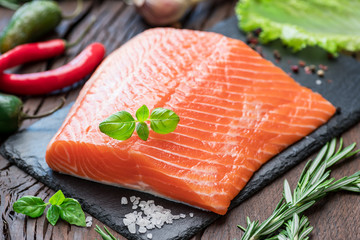 Wall Mural - Fresh salmon fillet on black cutting board with herbs and spices.