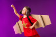 © LIGHTFIELD STUDIOS - smiling kid with plane wings and goggles standing with outstretched arm to fly isolated on purple