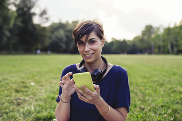 Sticker - Young adult woman using a mobile phone at the public park in summer