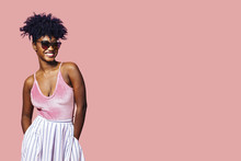 Smiling Young Girl With Sunglasses And Pink Top, Isolated On Pink Studio Background