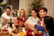 © Syda Productions - holidays and celebration concept - happy friends having christmas dinner at home, drinking red wine and clinking glasses
