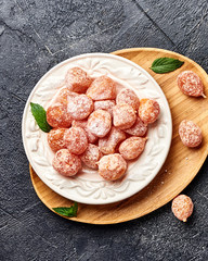 Poster - Dried sweet kumquat under powdered sugar on plate. Top view of dessert.