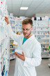 © Karanov images - Serious pharmacists man reaching for a medications among shelves at pharmacy drugstore