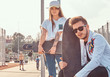 © Fxquadro - Close-up portrait of young trendy dressed hipster couple with skateboards posing at city sports complex on sunny day