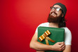© Vulp - Portrait of happy cheerful bearded hipster man holding a big gift for Christmas/ New Year over red background with free space for text