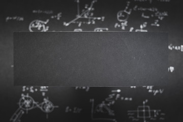 blank black paper with space for text. blurred background with science formula and equation.