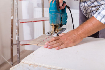 Installing laminate flooring. Carpenter cut parquet floor board with electric jigsaw.