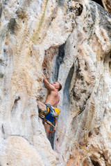 Young man rock climbing on white mountain in Thailand