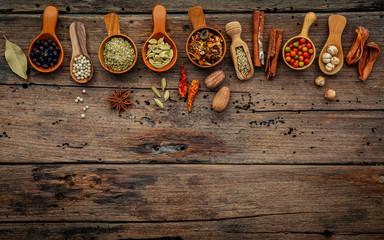 Poster - Various herbs and spices in wooden spoons on wooden background.